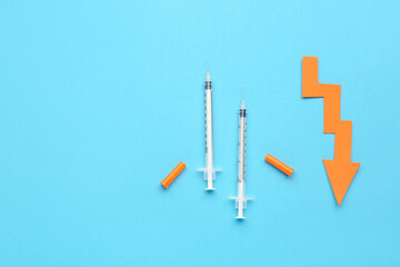 Syringes for insulin injection and arrow directed downwards on blue background