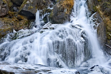 Russia. South of Western Siberia. One of the most beautiful waterfalls of the Altai Mountains on the Karasu River near the village of Chibit on the Chui tract, chained with ice of autumn frosts.