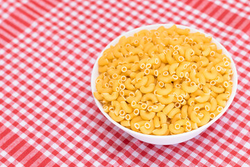 Uncooked Chifferi Rigati Pasta in White Cup on Red Checkered Towel. Fat and Unhealthy Food. Classic Dry Macaroni. Italian Culture and Cuisine. Raw Pasta