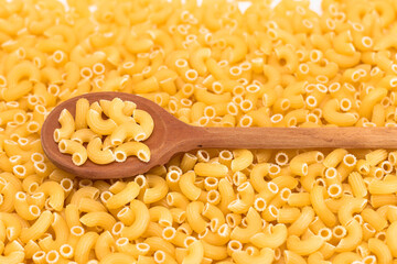 Uncooked Chifferi Rigati Pasta Background with Wooden Spoon. Fat and Unhealthy Food. Classic Dry Macaroni. Italian Culture and Cuisine. Raw Pasta