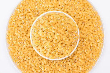 Uncooked Chifferi Rigati Pasta in White Plate on White Background. Fat and Unhealthy Food. Classic Dry Macaroni. Italian Culture and Cuisine. Raw Pasta