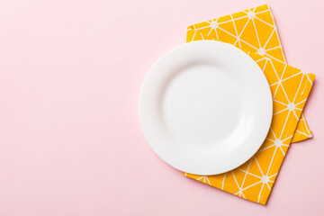 Top view on colored background empty round white plate on tablecloth for food. Empty dish on napkin with space for your design