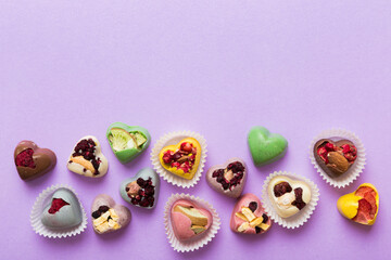 chocolate sweets in the form of a heart with fruits and nuts on a colored background. top view with space for text, holiday concept