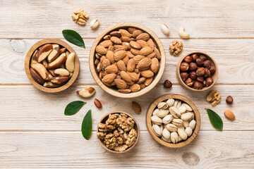 mixed nuts in wooden bowl. Mix of various nuts on colored background. pistachios, cashews, walnuts, hazelnuts, peanuts and brazil nuts