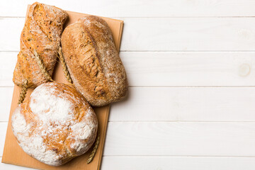 Freshly baked bread on cutting board against white wooden background. top view bread with copy space