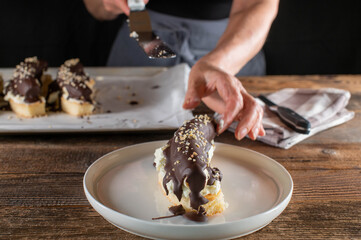 Woman with apron is serving a piece of chocolate covered banana on a plate
