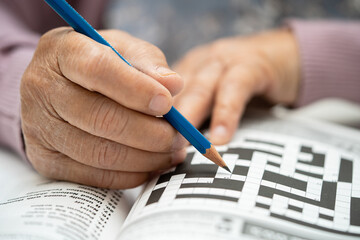 Alzheimer disease AD, Asian elderly woman playing sudoku puzzle game to practice brain training for...