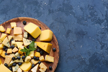 Plate with pieces of tasty cheese on blue background, closeup