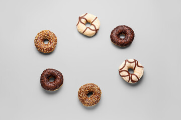 Frame made of sweet chocolate donuts on grey background