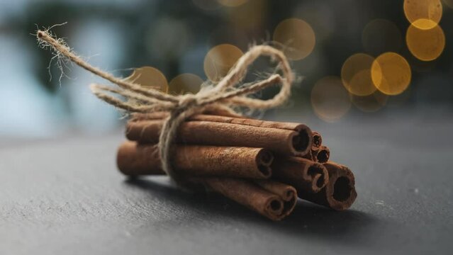 Dried cinnamon rolled in sticks and tied with rope on dark background