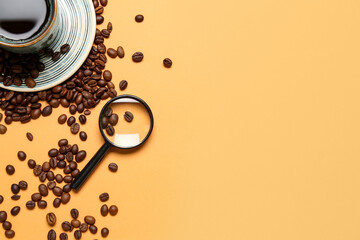 Magnifier and cup of coffee with beans on pale orange background