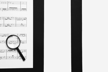 Magnifier with music sheet on black and white background