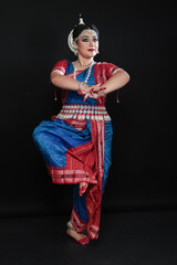 Woman performing Odissi dance in colorful costume. Indian classical dance forms.