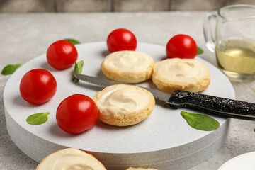 Board of tasty croutons with cream cheese and tomatoes on table