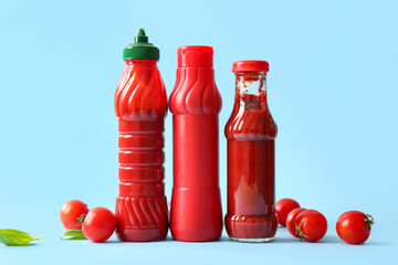 Bottles of ketchup and tomatoes on blue background