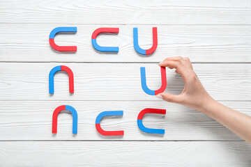 Female hand with frame made of magnets on white wooden background