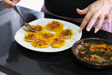 Close-up of a girl's hands preparing a plate with smashed green plantains to make 