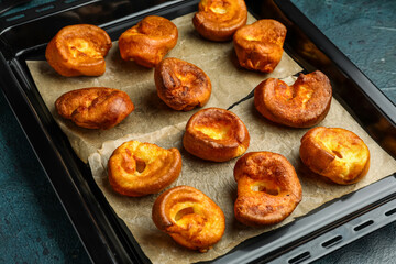 Baking tray with tasty Yorkshire pudding on blue background