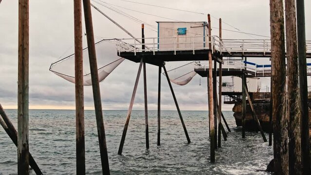 Rocky sea coast beach of Saint Palais in France with fishing hut and nets. Ocean coast with constraction for fish catching