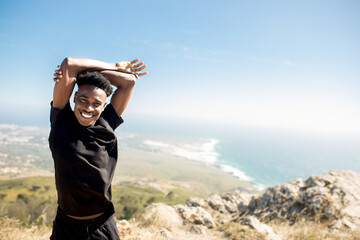Happy black man in sportswear doing stretching exercise for arms, exercising with perfect ocean view