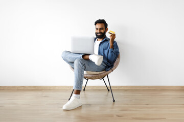 Arabic Guy Making Shopping With Laptop And Credit Card Indoors