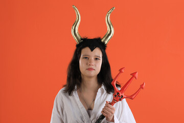 girl with halloween demon horns on orange background