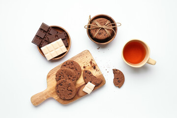 Wooden board with cookies, chocolate and cup of tea on white background