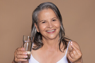 Happy european old woman with gray hair hold glass of water, vitamins capsule