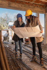Architecture, Women with hard hat, working on the construction of a building working in a team and blueprint reading.
