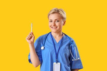 Female medical intern with pen on yellow background