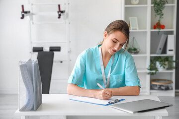 Female medical intern writing in clipboard at hospital