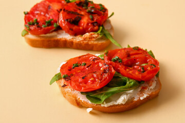 Sandwiches with tasty grilled tomatoes and arugula on yellow background