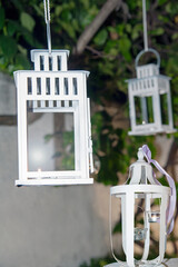 Metal candle holders hanging at the tree at night.