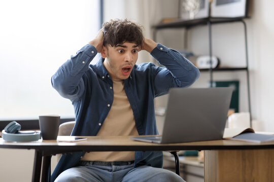Shocked Hispanic Businessman Looking At Laptop Having Issue Working Indoor