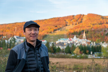 Naklejka premium Tourist posing for photos in front of Mont Tremblant village in Autumn, Quebec, Canada.