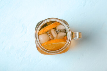 Mason jar of ice tea with orange on white background