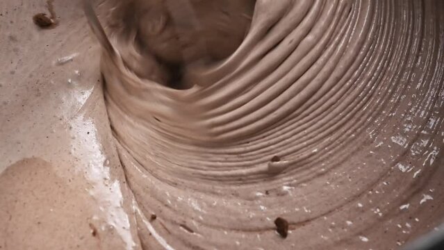 Chocolate pie dough kneading with cocoa using automatic mixer closeup. Tasty bakery desert cake preparation at kitchen