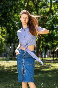 Young girl in a long denim skirt, summer park outdoors