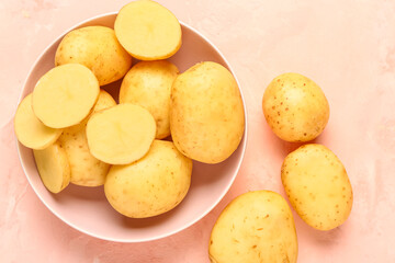 Bowl with raw baby potatoes on pink background