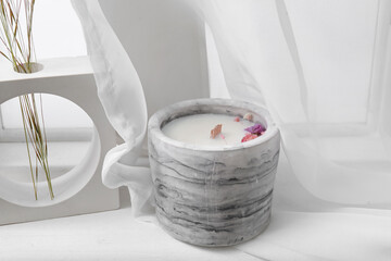 Holder with candle and decor on windowsill in room, closeup