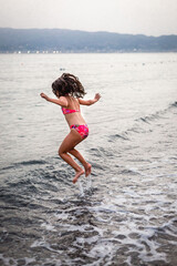 rear view of girl in red bikini jumping in the sea
