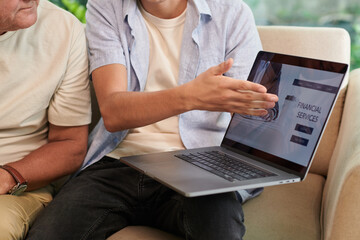 Cropped image of young man showing financial services website his grandfather