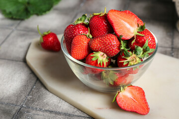 Bowl with fresh strawberries on grey tile background