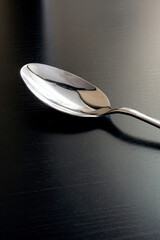 Metal spoon on black wooden table closeup