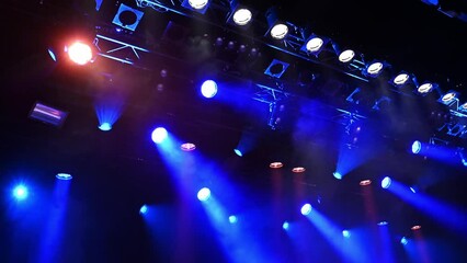 bright blue ceiling spotlights lights the stage through the stage fog during the musical concert or show