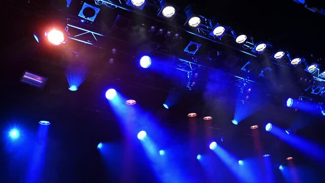 bright blue ceiling spotlights lights the stage through the stage fog during the musical concert or show