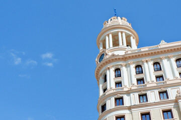 Fototapeta na wymiar Rounded tower on top of the historic colourful building. Antique architecture in the old city centre of Madrid, Spain. Stucco deco details of the walls