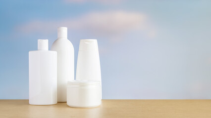 A set of cosmetic bottles and creams against a sky background