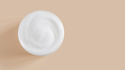 White cream in a jar on a beige background.