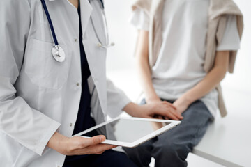 Doctor and child patient. The physician is holding tablet computer and reassuring a boy. The concept of ideal health in medicine